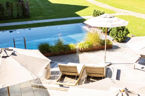 a patio with chairs and umbrellas next to a pool at Living & Spa Vitalhotel Edelweiss in Neustift im Stubaital