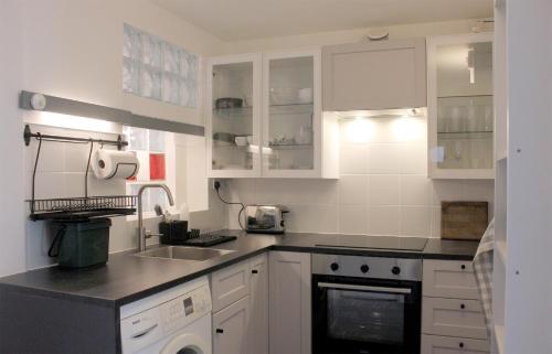 uma cozinha com armários brancos e um lavatório em Florence Park Flat em Oxford