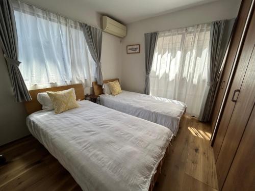 Dos camas en una habitación pequeña con ventanas. en 近藤沢駅の新装リノベーション一軒家 3LDK、無料駐車場完備、最大7名様までご利用可能, en Fujisawa