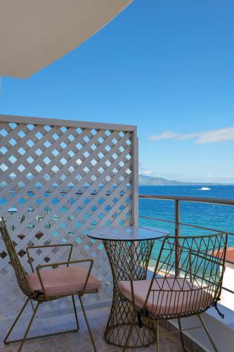 two chairs and a table on a balcony with the ocean at El Mare Hotel in Sarandë