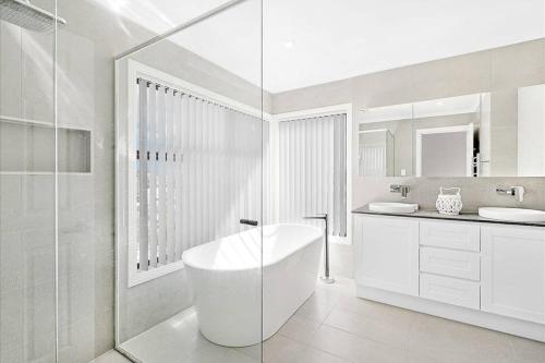 a white bathroom with a tub and a sink at KozyGuru Gold Coast Broadbeach Holiday Home in Gold Coast