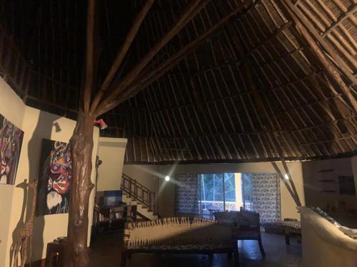 een kamer met een rieten plafond met stoelen en een boom bij Simba hoch2 in Galu