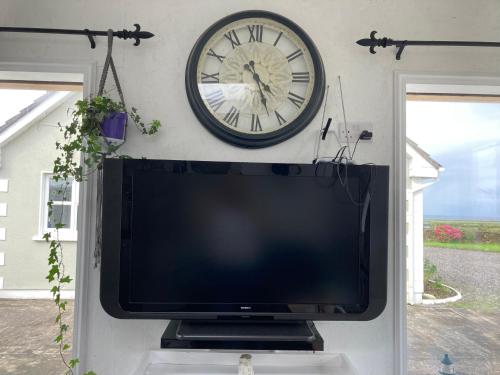 TV con reloj en la pared de arriba. en Wild Atlantic cabin en Sligo