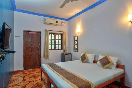 Om Sai Guest House في كالانغيُت: غرفة نوم بسرير وتلفزيون في غرفة
