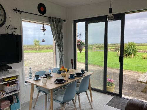 una sala da pranzo con tavolo, sedie e una grande finestra di Wild Atlantic cabin a Sligo