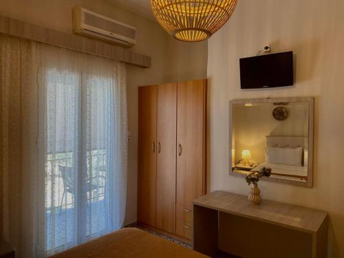 een slaapkamer met een spiegel, een dressoir en een televisie bij Galazia Nera Apartments in Áyios Andréas Messinias