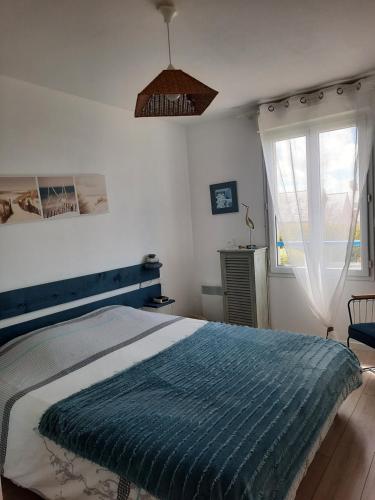 Un dormitorio con una cama con una manta azul. en Joli pavillon proximité ocean, en Saint-Nazaire