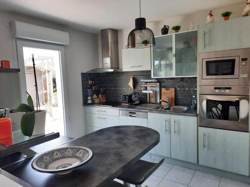 une cuisine avec des armoires blanches et une table à l'intérieur dans l'établissement Joli pavillon proximité ocean, à Saint-Nazaire