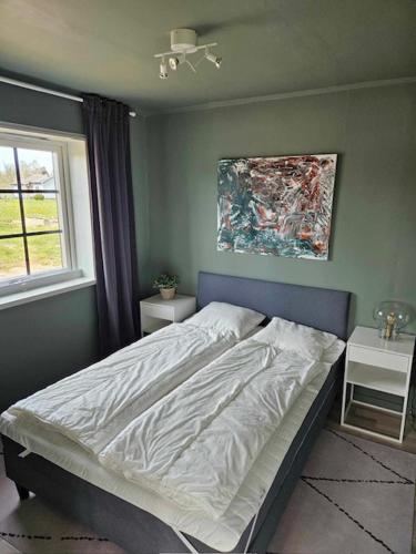 een slaapkamer met een bed en een schilderij aan de muur bij Ebbas stuga in Färjestaden