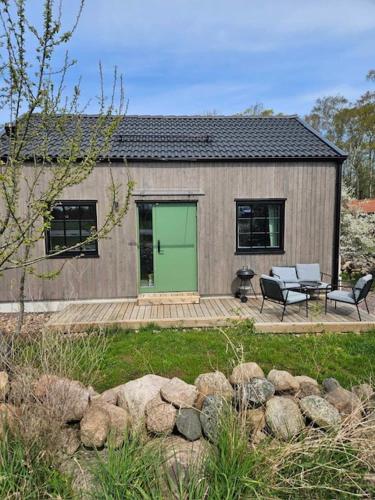 een klein huis met een groene deur en een patio bij Ebbas stuga in Färjestaden