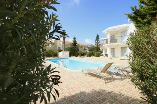 a swimming pool with two lounge chairs and a house at Danaos complex in Paphos City