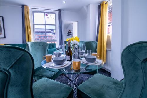 einen Tisch mit Teller und Tassen darauf mit grünen Stühlen in der Unterkunft Oxford Street - One Bed Lux in London
