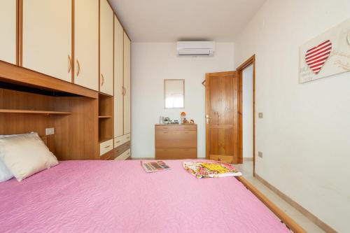 a bedroom with a bed with a pink blanket at AffittaSardegna-Casa Mirador in Agrustos