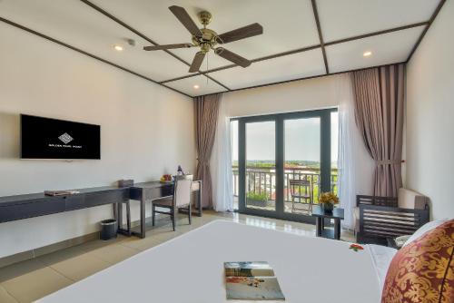sala de estar con ventilador de techo y escritorio en Golden Pearl Hoi An Hotel en Hoi An
