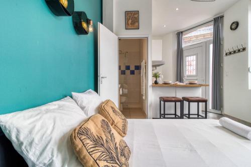 une chambre avec un lit blanc avec un mur bleu dans l'établissement La Main d'Or - Confort - Calme - Centre, à Abbeville