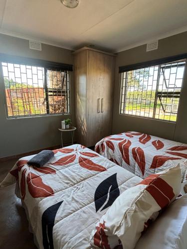 two beds in a room with two windows at Farmers Lodge in Piet Retief
