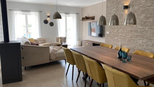 a dining room with a wooden table and yellow chairs at Villa Milandro - Luxus & Ruheoase in Lašći