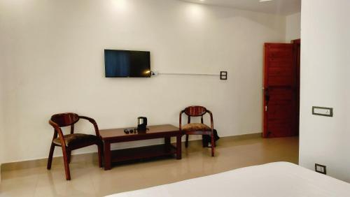 um quarto com uma secretária, 2 cadeiras e uma televisão em Hide Out Stays em Dharamshala