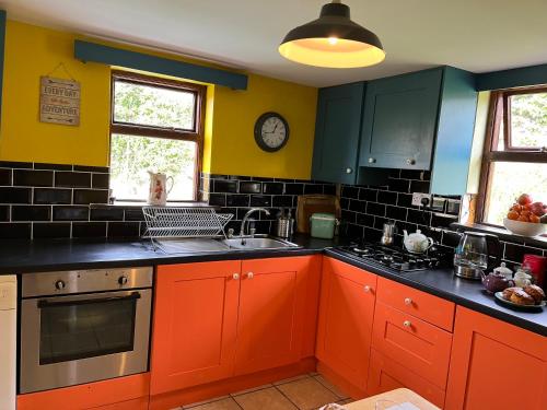 uma cozinha com armários laranja e um relógio na parede em Seaview House Reenard South em Cahersiveen