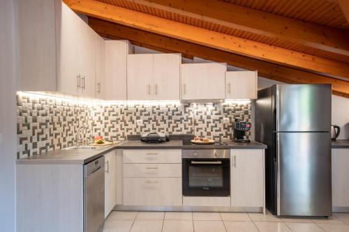 a kitchen with white cabinets and a stainless steel refrigerator at La perla loft in Sami