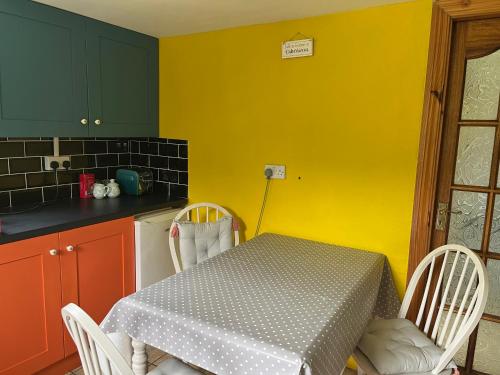 a kitchen with a table and chairs and a yellow wall at Seaview House Reenard South in Cahersiveen