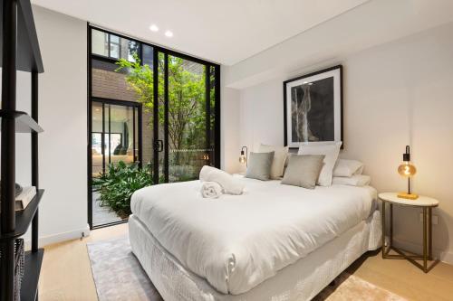 a bedroom with a large white bed and large windows at Luxurious Parkside 4BR Terrace House w/Garage in Sydney