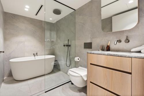 a bathroom with a tub and a toilet and a sink at Luxurious Parkside 4BR Terrace House w/Garage in Sydney