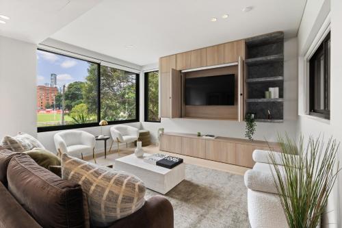 a living room with a couch and a tv at Luxurious Parkside 4BR Terrace House w/Garage in Sydney