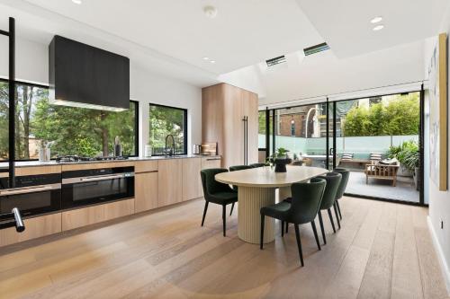 a kitchen with a table and chairs and a kitchen with windows at Luxurious Parkside 4BR Terrace House w/Garage in Sydney