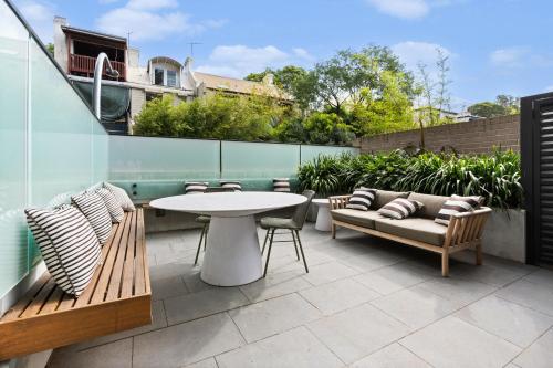a patio with two benches and a table and chairs at Luxurious Parkside 4BR Terrace House w/Garage in Sydney