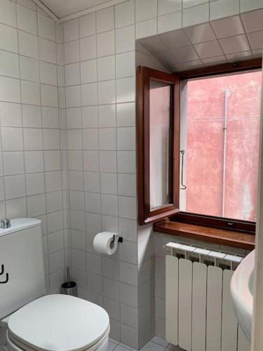 a bathroom with a toilet and a window at La Casa di Mezzo - The Middle House in Monte Marcello