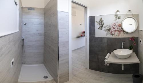 uma casa de banho com um chuveiro, um lavatório e um espelho. em Appartamento Sorso em Sorso
