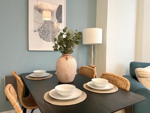 a dining room table with plates and a vase at Lush Porthcawl Large Spacious 2 bedroom Apt, Garden, Prime Location in Porthcawl