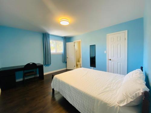 een blauwe slaapkamer met een bed en een bureau bij Riverwood Home in Mississauga