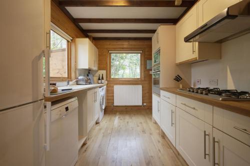 a kitchen with white cabinets and a wooden floor at Heron Lodge with Hot-tub in Carlisle