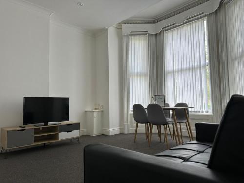 ein Wohnzimmer mit einem TV und einem Tisch mit Stühlen in der Unterkunft Apartments 7 Greenfield Road in Liverpool