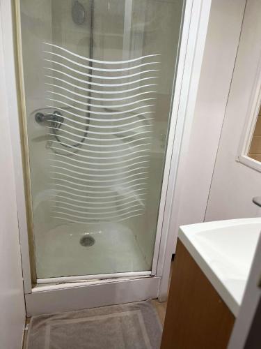 une douche avec une porte vitrée dans une salle de bain dans l'établissement Mobil Home 4 personnes, à Nances