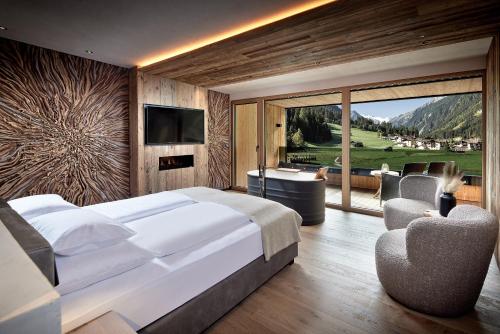 a bedroom with a large white bed and a television at Living & Spa Vitalhotel Edelweiss in Neustift im Stubaital