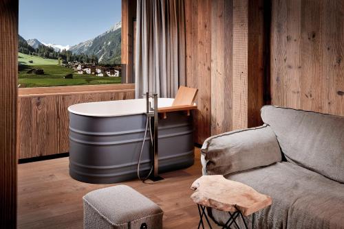 a bath tub in a room with a couch and a window at Living & Spa Vitalhotel Edelweiss in Neustift im Stubaital