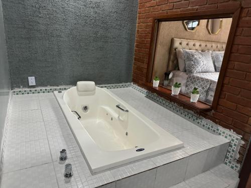 uma banheira na casa de banho com um espelho em Chalé 08 com hidro no coração de Penedo em Itatiaia