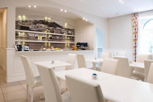 a dining room with white tables and white chairs at Certosa Suite in Naples