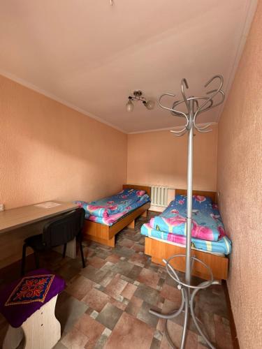 a room with two beds and a desk and a table at Dos Guesthouse in Bishkek