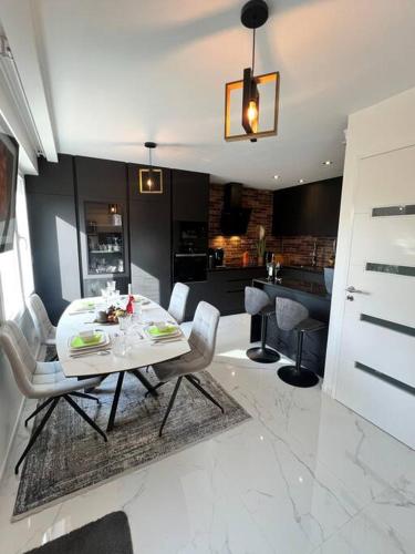 une salle à manger et une cuisine avec une table et des chaises blanches dans l'établissement Maison luxueuse - 15 mins de paris, à Bonneuil-sur-Marne