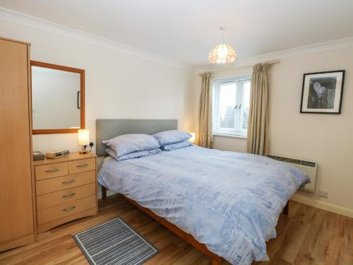 een slaapkamer met een bed, een ladekast en een spiegel bij Paws-A-While in Norwich