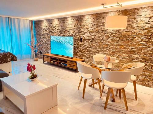a living room with a table and a tv at DOMINO - Superbe studio de standing in Leukerbad