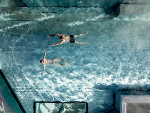 2 personas nadando en una piscina en Das Central – Alpine . Luxury . Life, en Sölden