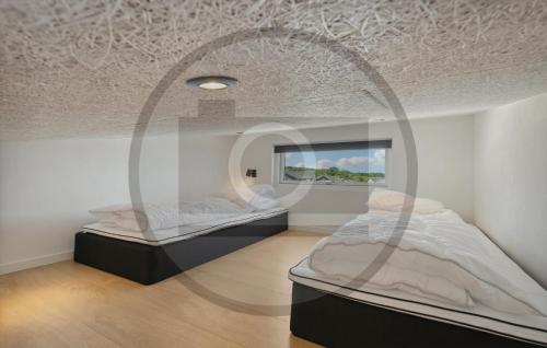 Beautiful Home In Brkop With Sauna في Børkop: سريرين في غرفة مع نافذة دائرية
