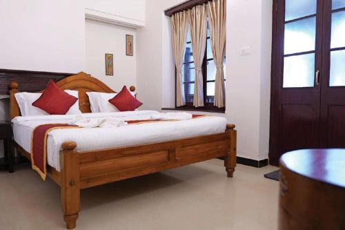 a bedroom with a wooden bed with red pillows at Lakefront Home Hotel in Ooty