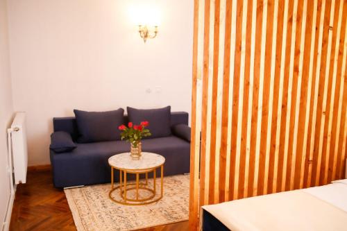 un sofá azul y una mesa con un jarrón de flores en Joseph Hayn Apartments, en Sighişoara