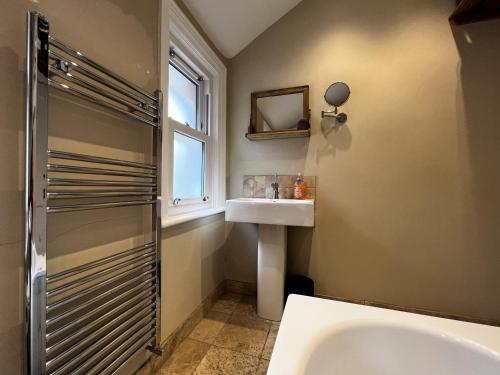 uma casa de banho com uma banheira, um lavatório e uma janela em Bell Cottage em Cowes